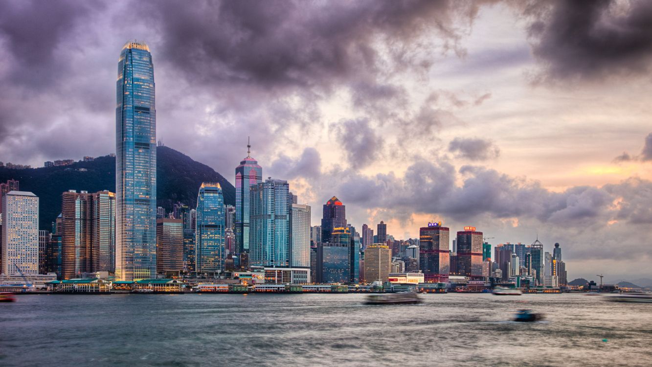 city skyline across body of water under cloudy sky during daytime