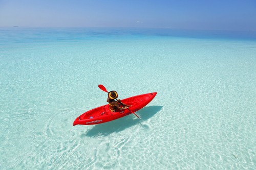 Image person in red kayak on white sand beach during daytime