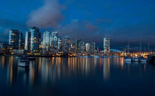 Image city skyline across body of water during night time