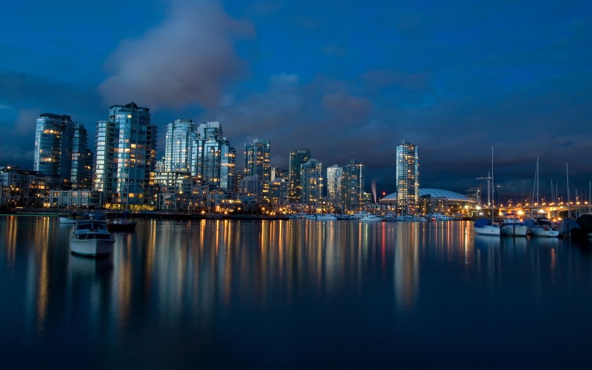 city skyline across body of water during night time