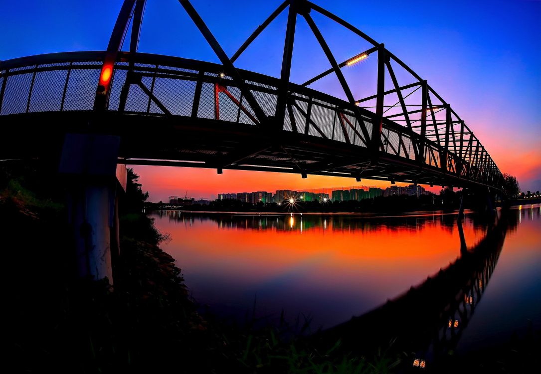 silhouette of bridge over body of water during sunset