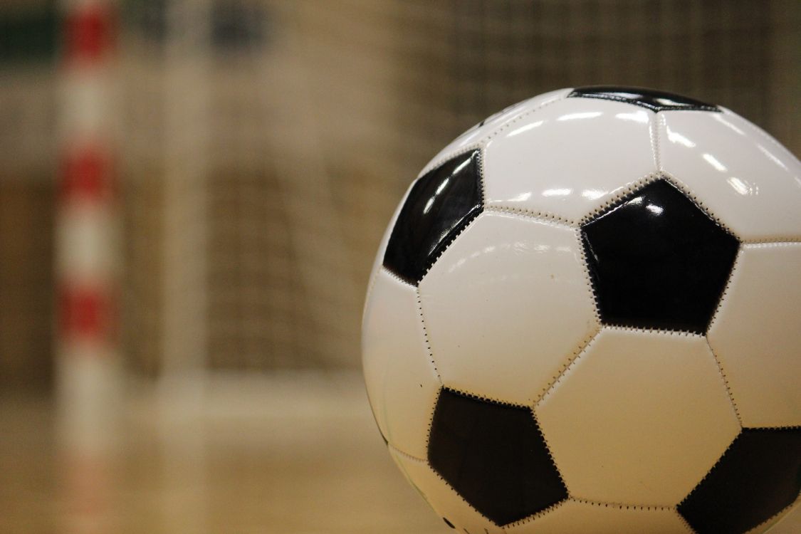 white and black soccer ball on brown wooden floor