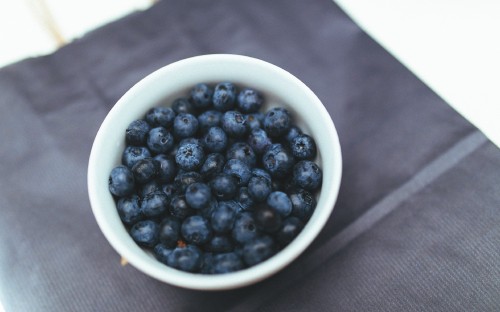 Image black round fruits in white ceramic bowl