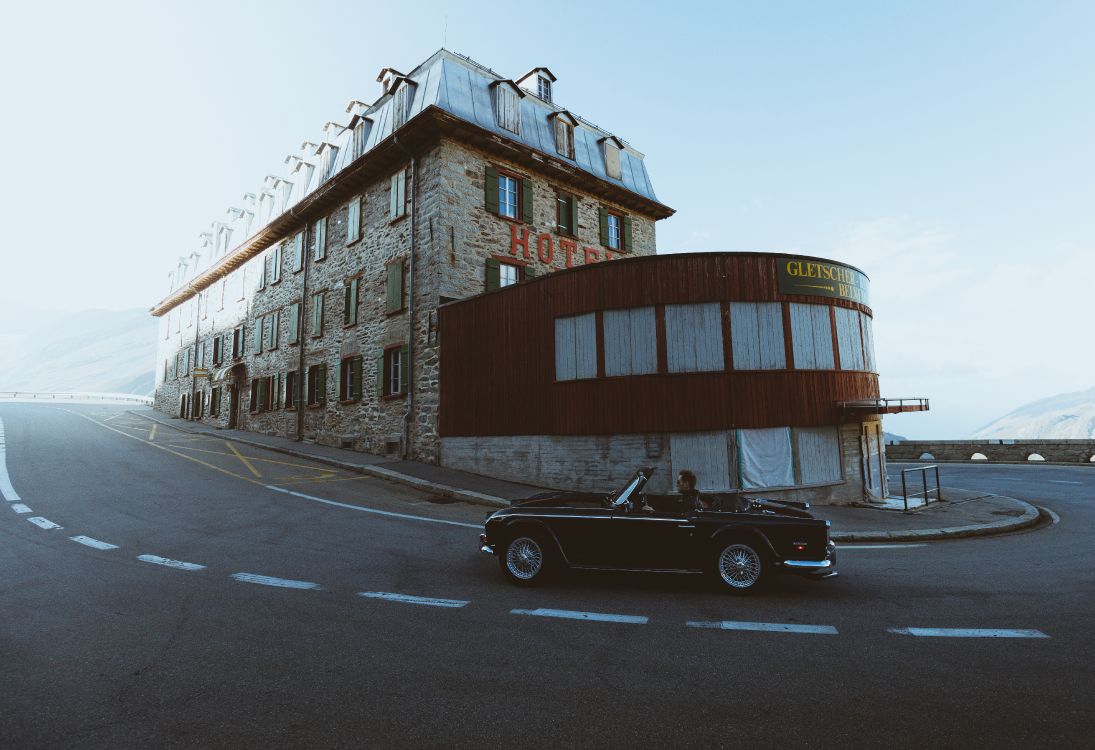 black coupe parked beside brown concrete building during daytime