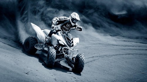 Image man riding atv on gray sand