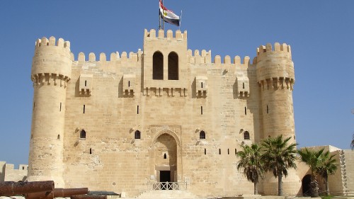 Image brown concrete building with flags during daytime