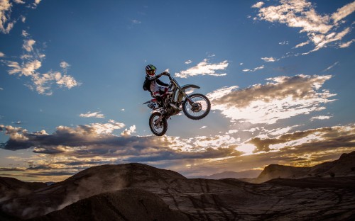 Image man riding motocross dirt bike on brown mountain under blue sky during daytime