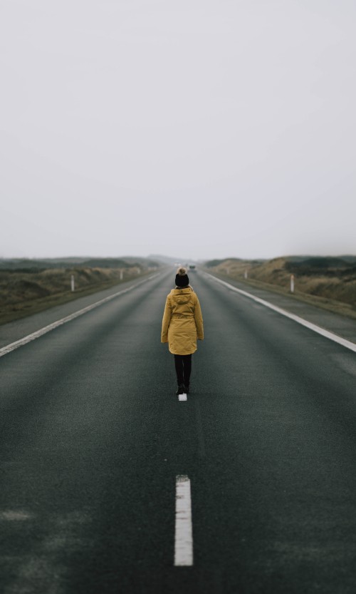 Image woman in brown coat standing on road during daytime