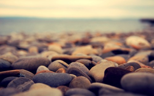 Image gray and black stones near body of water during daytime