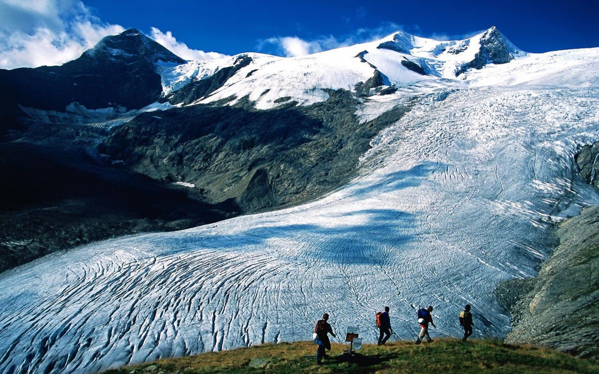 people walking on snow covered ground near snow covered mountain during daytime