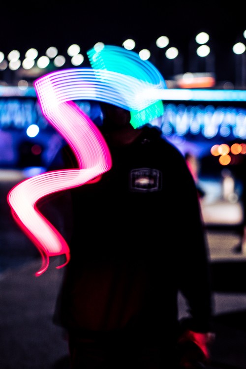 Image man in black hoodie standing near blue and white light during night time