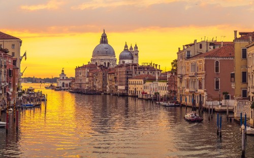 Image white and brown concrete building beside body of water during sunset