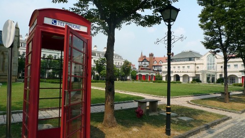 Image red telephone booth near green trees during daytime