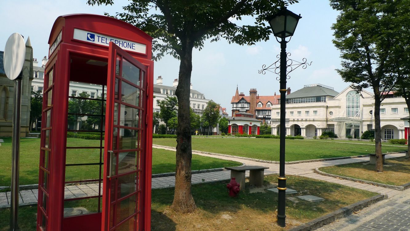 red telephone booth near green trees during daytime