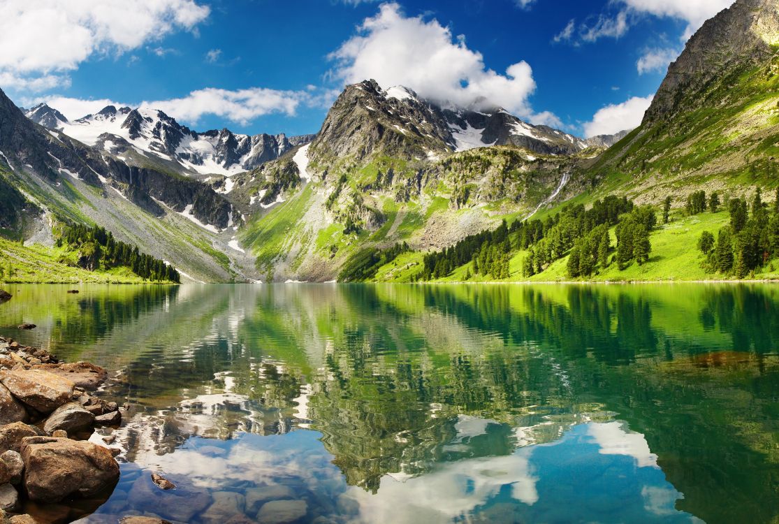 green and white mountains near lake under blue sky during daytime