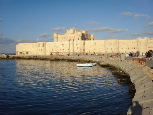 Image white boat on body of water near concrete building during daytime