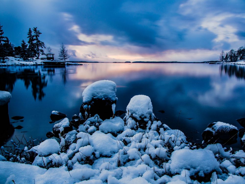 gray rocks on body of water under cloudy sky during daytime