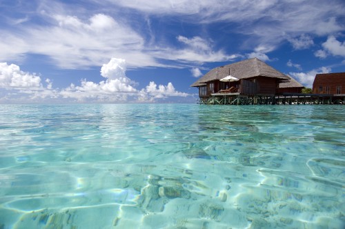 Image brown wooden house on body of water under blue sky and white clouds during daytime