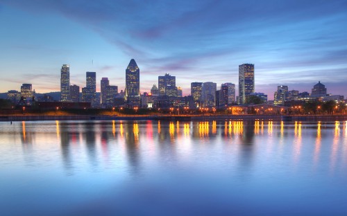 Image city skyline across body of water during night time