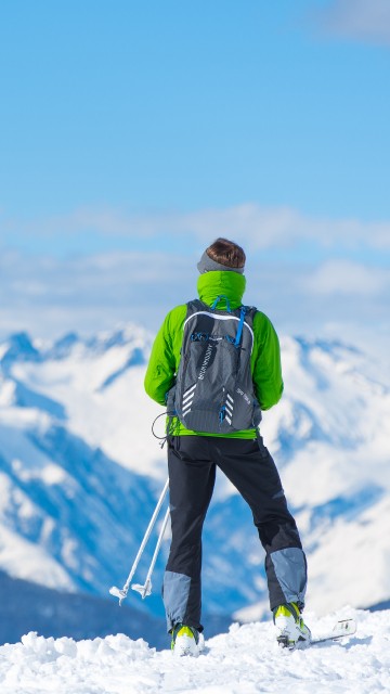 Image man in green jacket and black pants standing on snow covered ground during daytime