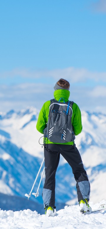 Image man in green jacket and black pants standing on snow covered ground during daytime