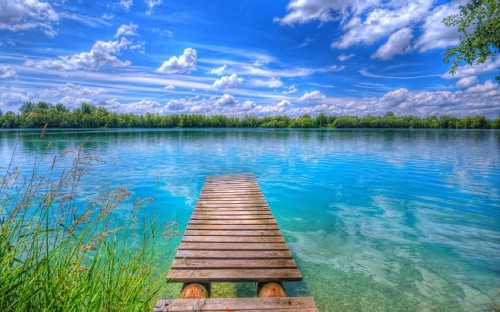 Image brown wooden dock on lake under blue sky and white clouds during daytime