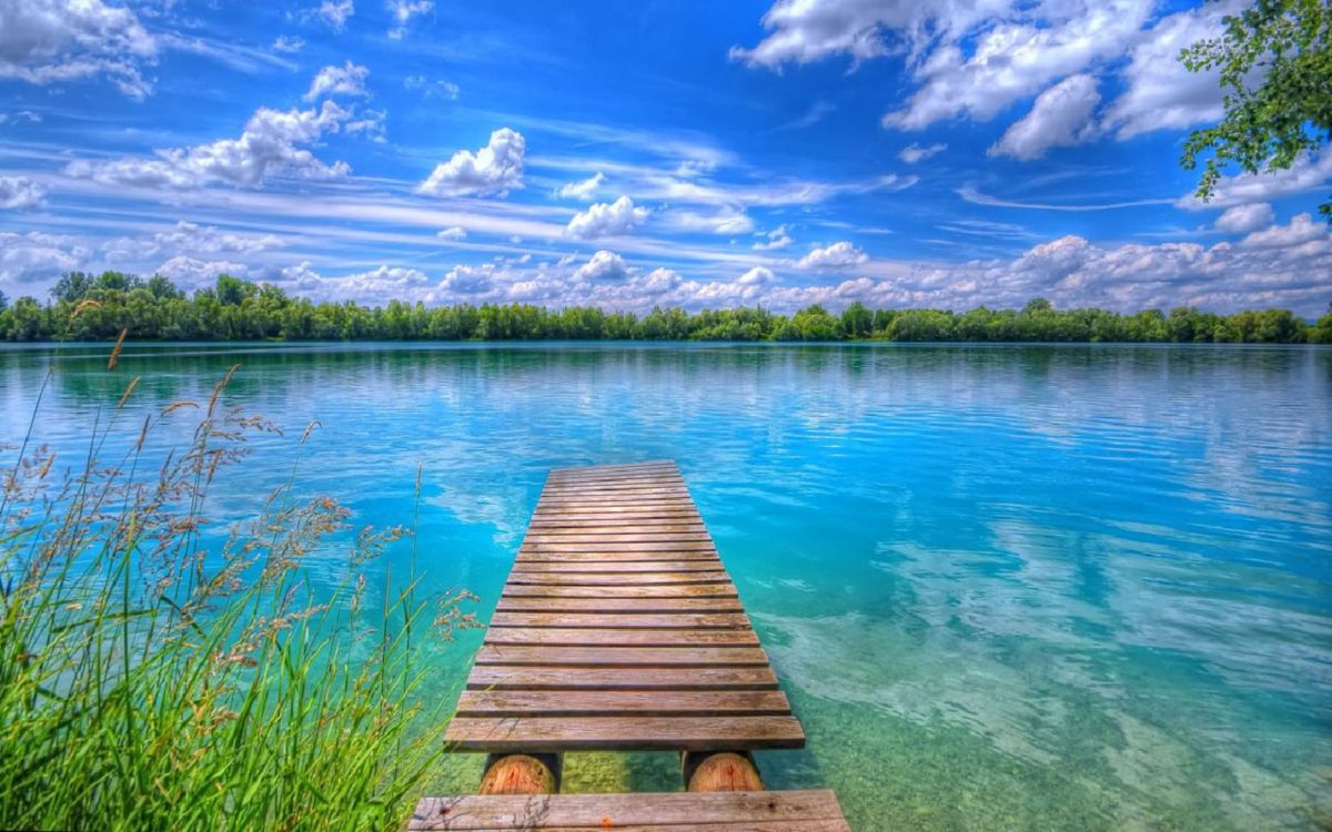 brown wooden dock on lake under blue sky and white clouds during daytime