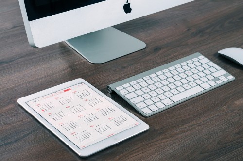 Image silver imac and apple keyboard on brown wooden desk