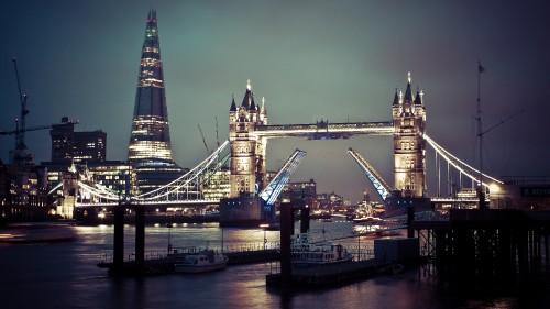 Image brown and black bridge near city buildings during night time