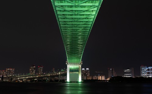 Image green bridge over body of water during night time