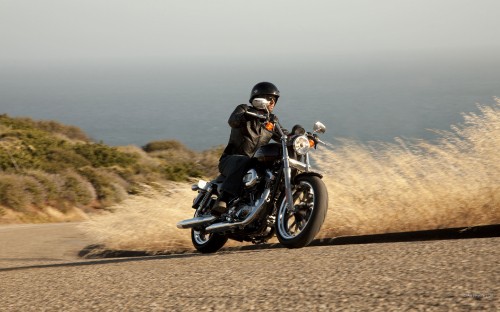 Image man in black jacket riding black motorcycle on brown field during daytime