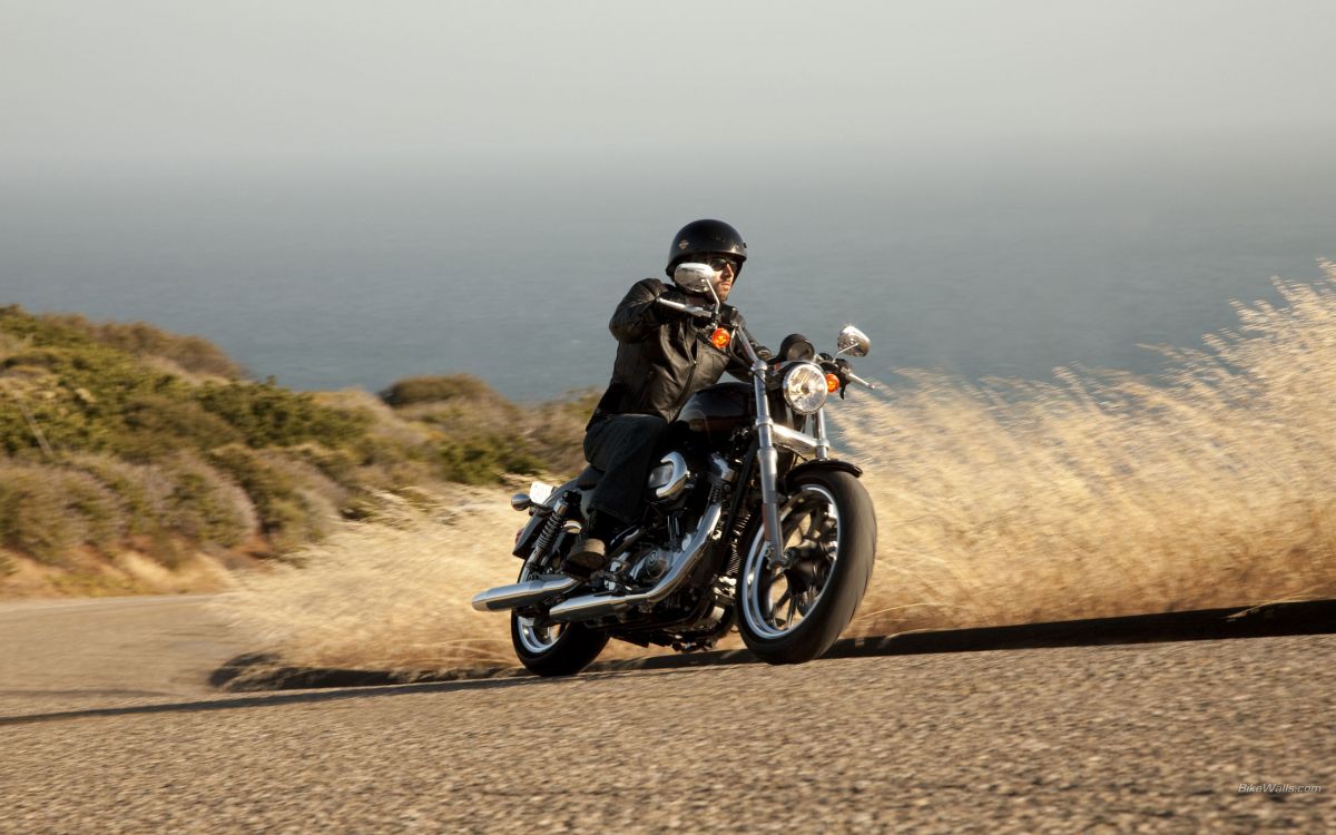 man in black jacket riding black motorcycle on brown field during daytime