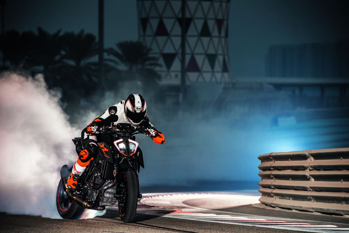 man in black and orange motorcycle helmet riding on black and orange sports bike