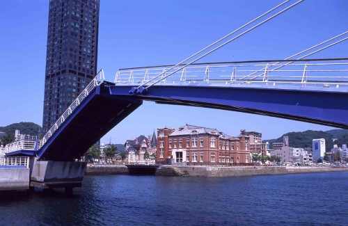 Image white and brown concrete building near bridge under blue sky during daytime