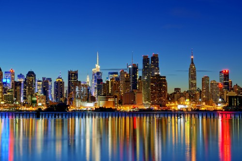 Image city skyline across body of water during night time