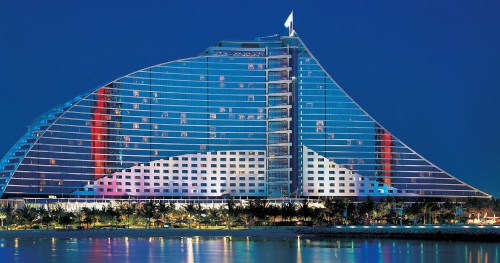 Image blue and white glass building near body of water during night time