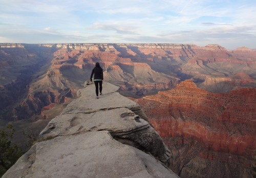 Image man in black jacket standing on rock formation during daytime