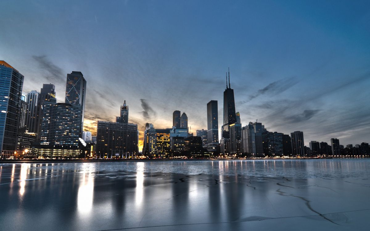 city skyline across body of water during night time