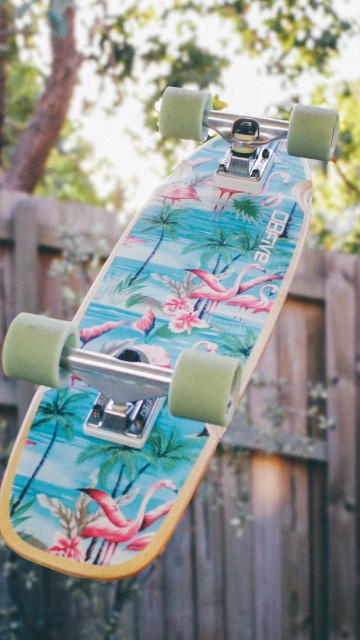 Image green and black skateboard on brown wooden fence during daytime