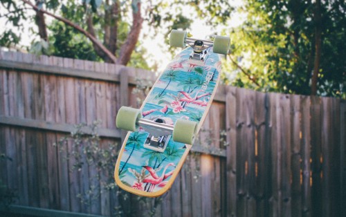 Image green and black skateboard on brown wooden fence during daytime