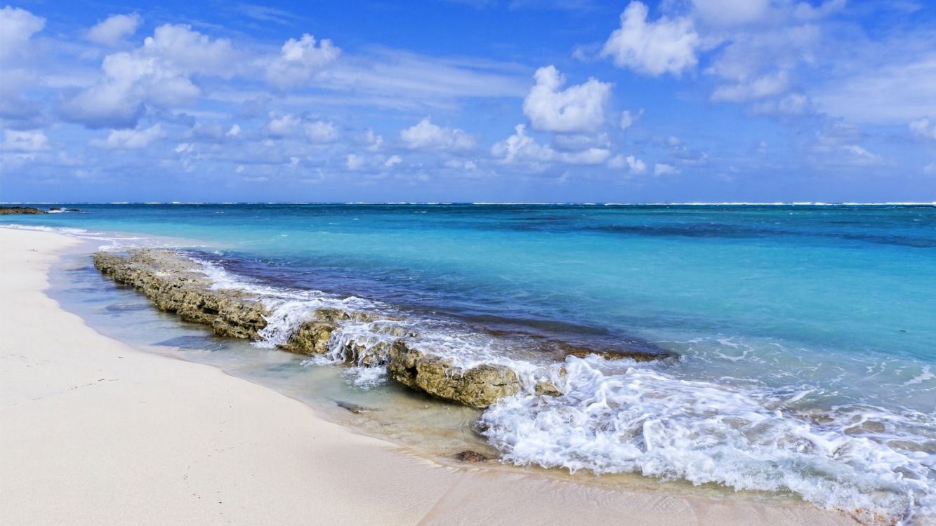 sea waves crashing on shore under blue and white cloudy sky during daytime