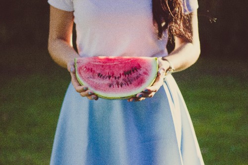 Image woman in white and blue dress holding sliced watermelon