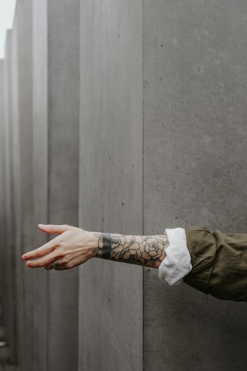 Person in Brauner Jacke Mit Schwarzem Tattoo an Der Linken Hand. Wallpaper in 2624x3936 Resolution
