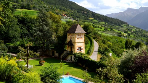 Image brown concrete building near green trees and mountains during daytime