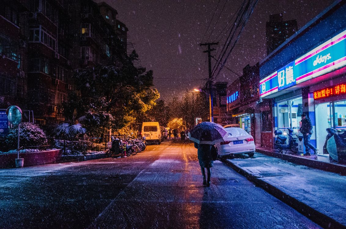 person in black jacket and black pants walking on sidewalk during night time