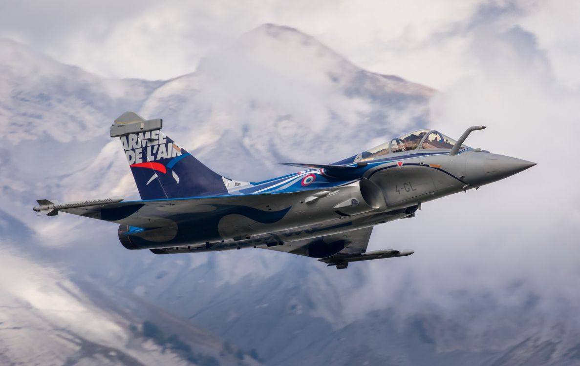 blue and white jet plane flying over the mountain