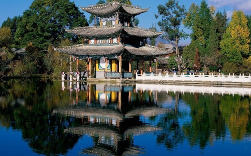 Image brown and white temple near body of water during daytime