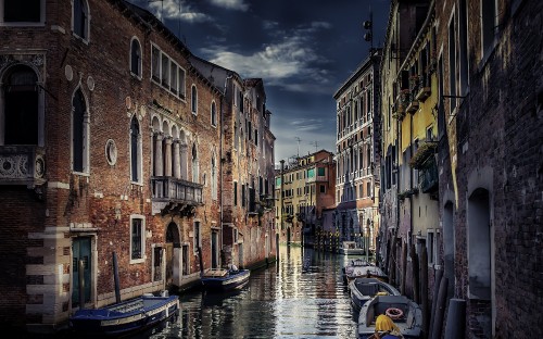 Image boat on river between buildings during daytime