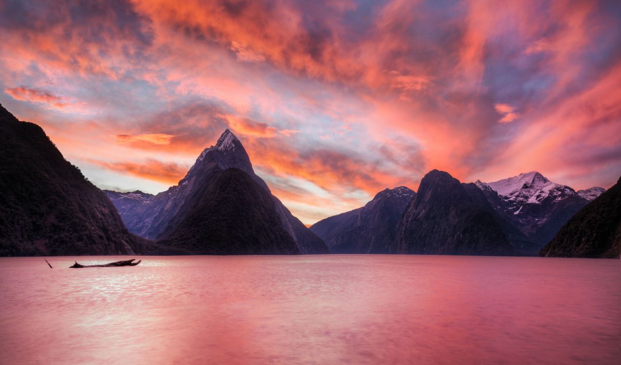 body of water near mountain during sunset