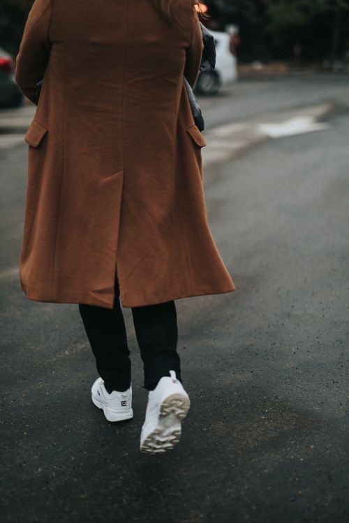 person in brown coat and black pants wearing white sneakers